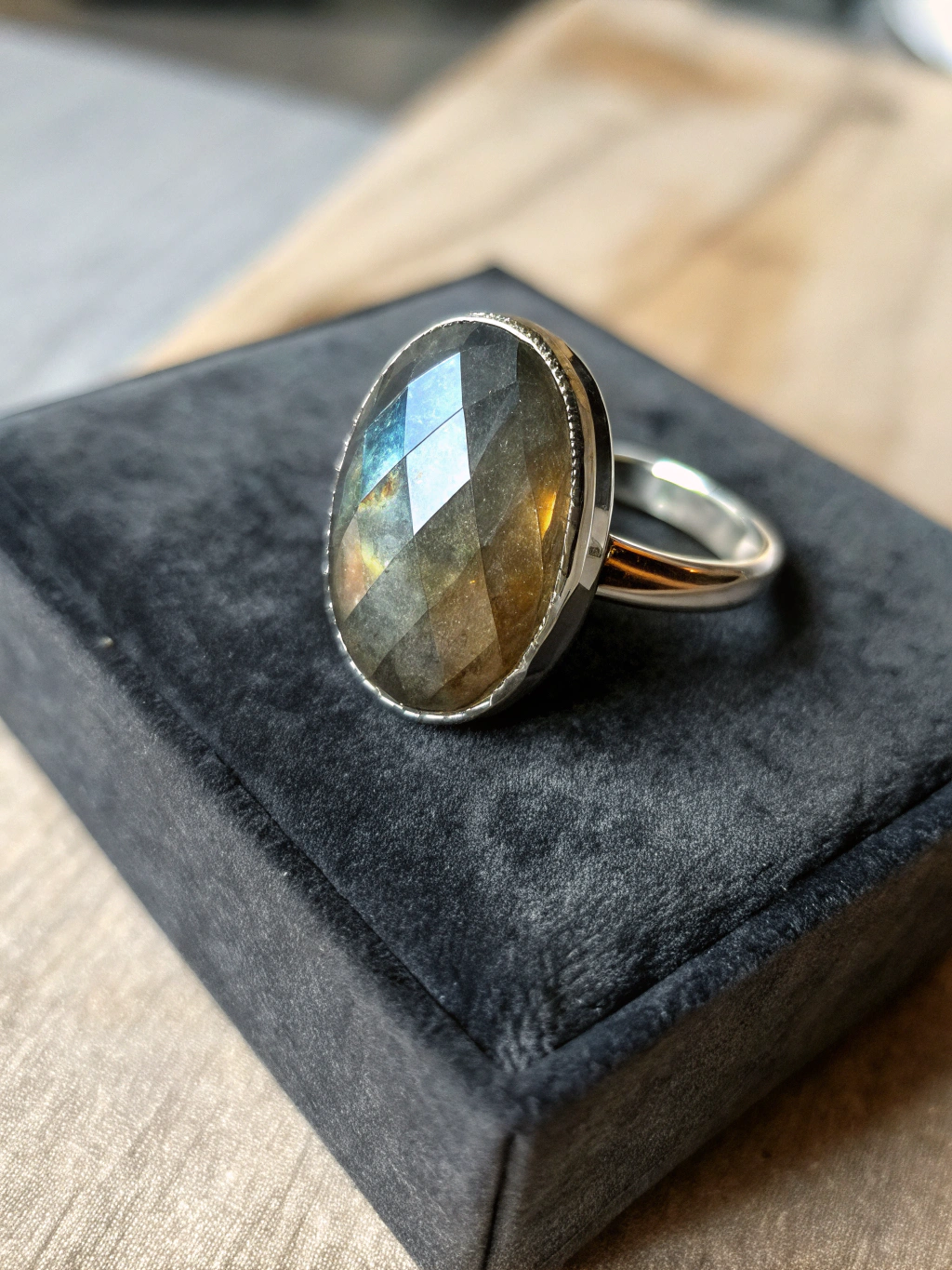 Handcrafted sterling silver ring showcasing a luminous raw labradorite cabochon on an unglazed slate surface